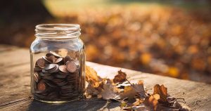 Kolikoita lasipurkissa syksyisessä säässä